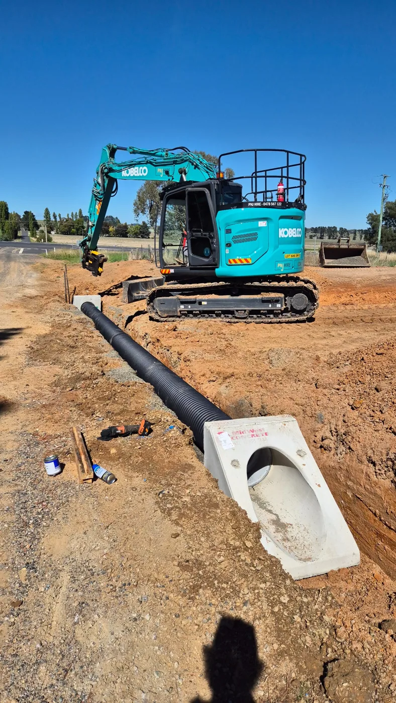 Excavator working alongside installed stormwater drainage