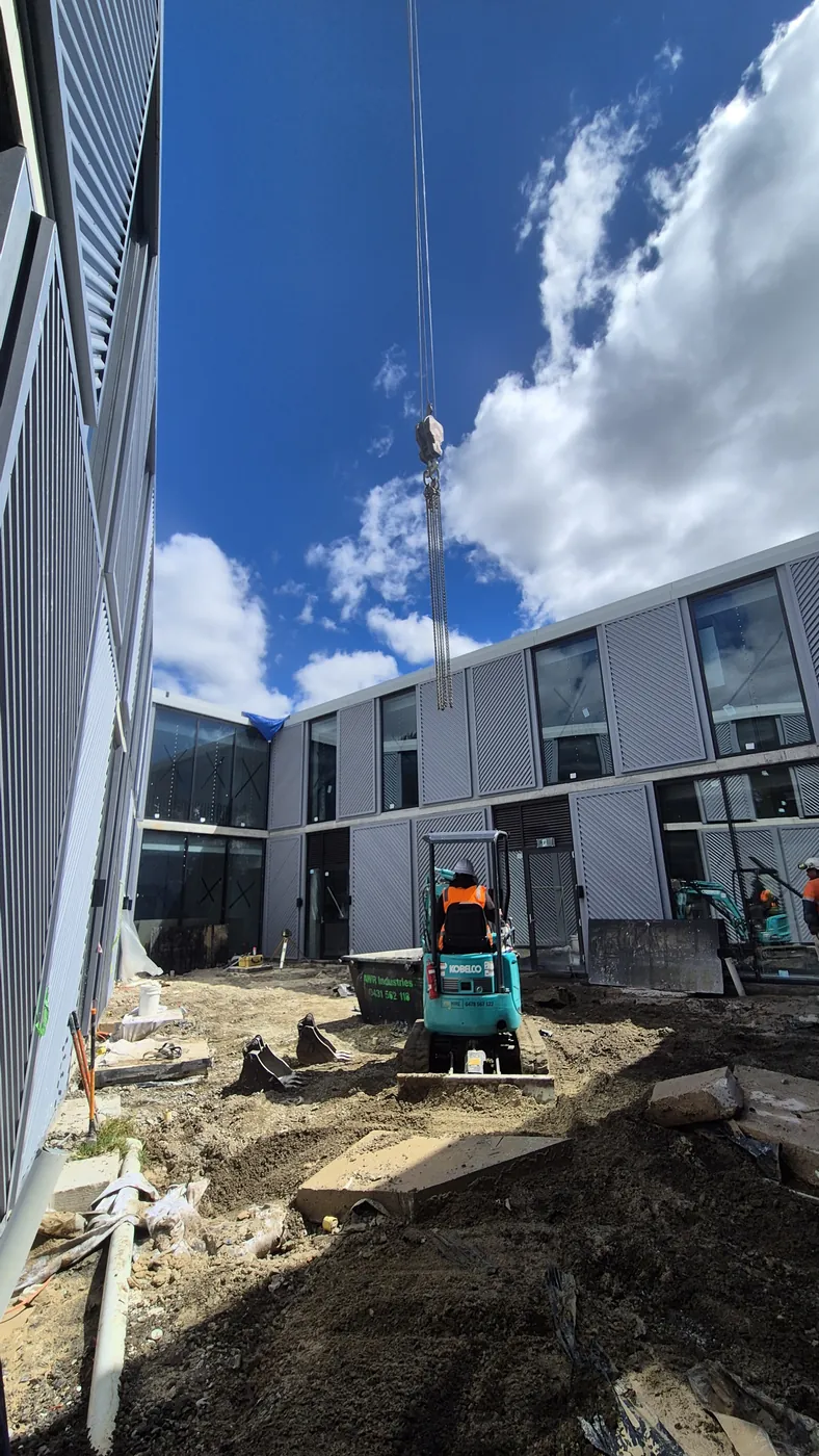 Mini excavator working in a tight courtyard between buildings